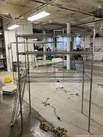 Full view of assembled Metro metal shelving rack in warehouse space, showing four wire shelves and four poles with medium metal finish.