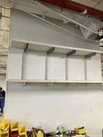 Photo showing two wall-mounted shelving units with multiple horizontal wooden shelves supported by black metal brackets on vertical rails.
