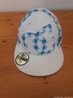 Front and top view of blue and white checkered DC Shoes 59FIFTY fitted cap with large DC logo on front and flat white brim, showing condition and design details.