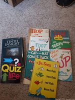 Lot of Dr. Seuss books and two additional books laid out on carpet floor, showing titles and covers