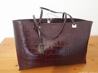 Photo shows front exterior of maroon handbag with crocodile texture and double straps.
