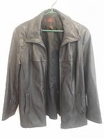 Black leather jacket hanging on green hanger showing front detail and collar.