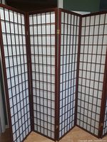 Diagonal view showing full four-panel wooden folding screen with white translucent panels in a grid design.
