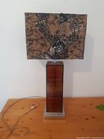 Front view of the vintage lamp showing rectangular brown base and patterned shade on wooden table.