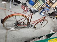 Left rear 3/4 view of the bicycle showing the steel frame, rear tire, saddle, rear luggage rack, and drivetrain.