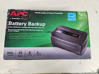 Box of APC Battery Backup showing specifications such as 650VA, 320 Watts, 43 minutes runtime, 3 outlets, 3 year warranty.