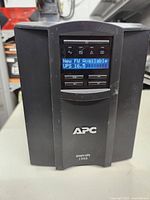 Front view of APC Smart-UPS 1500 showing digital LCD display indicating 'New FW Available UPS 16.5'.