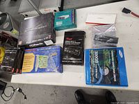 View of all PC parts on table including ASRock motherboard box, Samsung hard drive box, Rosewill card reader box, and various other components.