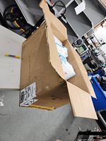 Opened cardboard box containing smaller boxes of disposable masks. 22 boxes visible inside, some labeled with 'AILE' brand and 'Disposable Protective Mask'. Each box contains 50 masks.