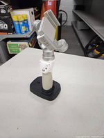 DJI Osmo Mobile smartphone stabilizer mounted on charging base on a tabletop. Shows front side with control buttons and clamp for smartphone.