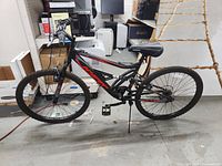 Full side profile of the black and red Hyper Shocker 26-inch adult mountain bike in a warehouse.