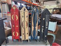 Four small, hand-painted wooden cabinets standing upright, showing front with celestial artwork and signs of wear and warping on doors.