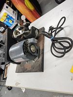 Side angle photo showing machine body, motor, power cord attached with visible rust and wear on metal base.