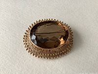 Front view of oval citrine set in 14K gold wire surround on white background