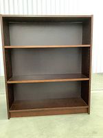 Front view of wooden bookshelf with three shelves and loose back panel
