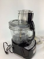 Single-unit Cuisinart food processor base with attached clear bowl and feeding chute with handle, black base with buttons.
