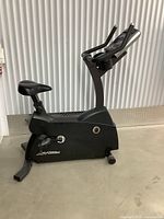 Side view of matte black LifeFitness exercise bike showing frame, seat, pedals