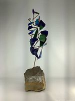 Full front view of sculpture showing painted leaves and rock base