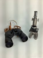 Photo showing vintage Birks microscope and binoculars with strap side by side.
