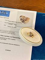 Ring displayed in white jewelry box alongside appraisal certificate.