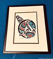 Framed artwork showing the full killer whale print and frame, photographed on a blue surface.