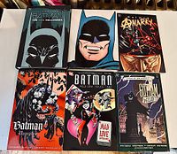 Top-down view of all six Batman graphic novels arranged in two rows of three. Covers include a Batman mask close-up, a detailed Anarchy cover, and cover art with Harlequin and Joker characters.
