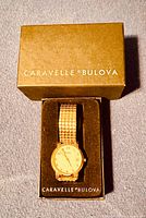 Goldtone men's wristwatch in original brown box labeled 'CARAVELLE by BULOVA' with black cushioned insert.