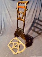 Full view of the Pack-N-Roll hand truck dolly in standing position, showing foldable base and handle.