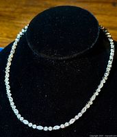 Necklace displayed on black velvet stand showing the continuous line of alternating shaped CZ stones.