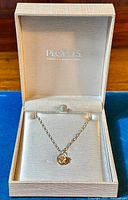 Sterling silver necklace with rose pendant displayed inside a beige textured jewelry box with 'Peoples Jewelry & Stationery Store' branding on the inside of the lid.