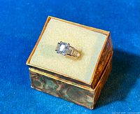 Front angle view of the 925 sterling silver trinity-style ring with clear CZ stones in a jewelry box on a blue background.
