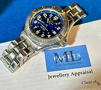 Front view of watch resting on appraisal document showing blue dial and bracelet