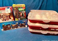Photo of three storage bins with clear lids showing assorted Christmas balls inside alongside boxed Holiday Village buildings, boxed Tree Dazzler light show and Santa's Christmas Train set.