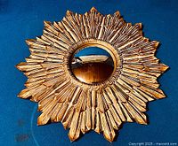 Top-down view of entire sunburst mirror on blue backdrop