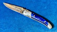 Knife open on blue background, full view of handle and blade