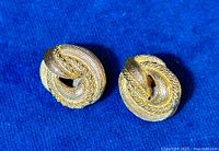 Close-up front view of both gold-tone clip earrings displaying the textured twisted loop design.