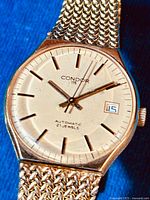 Front view of the watch face showing gold-tone case, dial with hour markers, hands and date display, marked with Condor 115 Automatic 21 Jewels.