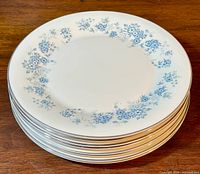 Stack of eight white ceramic dinner plates with blue floral pattern around the edge and silver rim, good overall condition