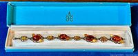 Full length view of the sterling silver bracelet set with various shades of amber cabochons inside the original blue Birks Jewellers box.