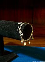 Photo showing the full length of the sterling silver curb link charm bracelet with six charms on display stand.