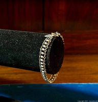 Vintage sterling silver fancy link bracelet displayed on black velvet stand against wooden background