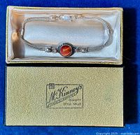 Top view of the sterling silver bracelet with carnelian center stone displayed in original gold and black box with satin lining.