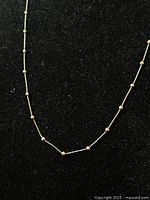 Close-up photo showing the detailed twist links and round balls of the silver chain on a black background.