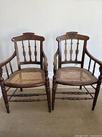Pair of antique dark wood armchairs with cane seats, showing overall condition and style.