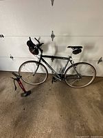 Full side profile image of the Cannondale road bicycle including bottle holder and a bike pump on the floor.