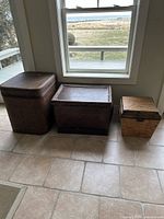 Three large natural storage bins placed together on a tiled floor near a window, showing shape, size, and color variation.