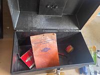 Open black metal toolbox showing empty interior with some papers