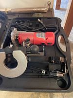 Red handheld power router and accessories fitted inside a black carrying case.