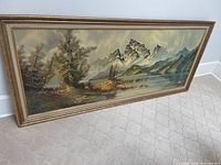 Full view of vintage mid century landscape art print, horizontal format with mountainous lake scene and trees, framed in gold.