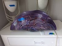 Photo showing the front view of the purple glass shell with colorful swirls on outer surface, placed on white surface.
